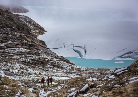 Three people hiking down to a glacier