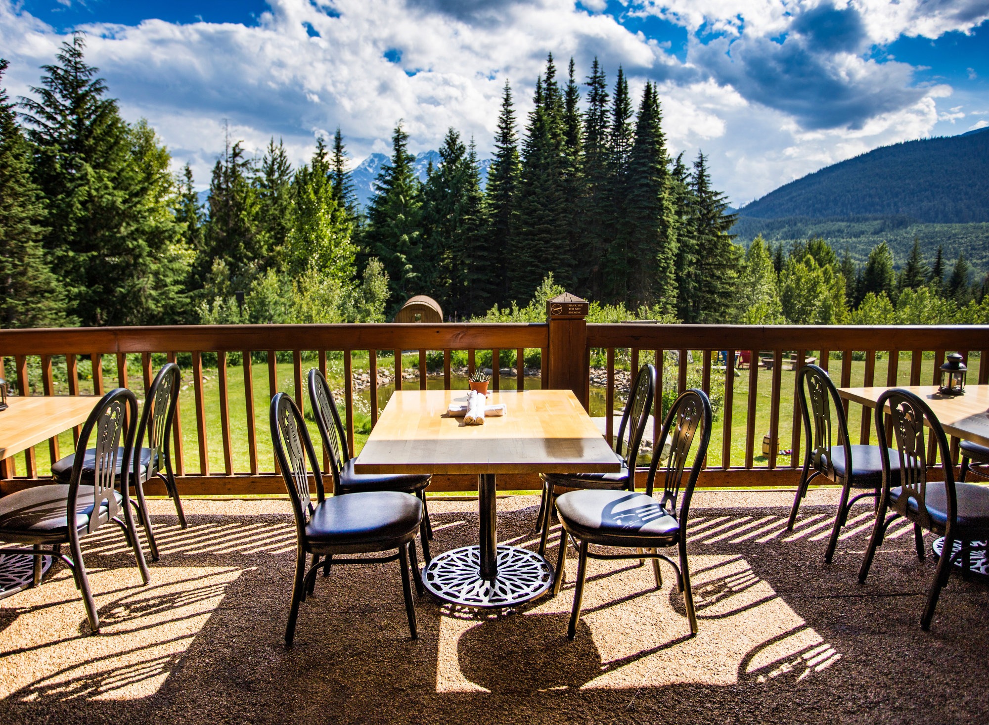 Table with four seats on the balcony on a sunny day with a view of the mountains and trees