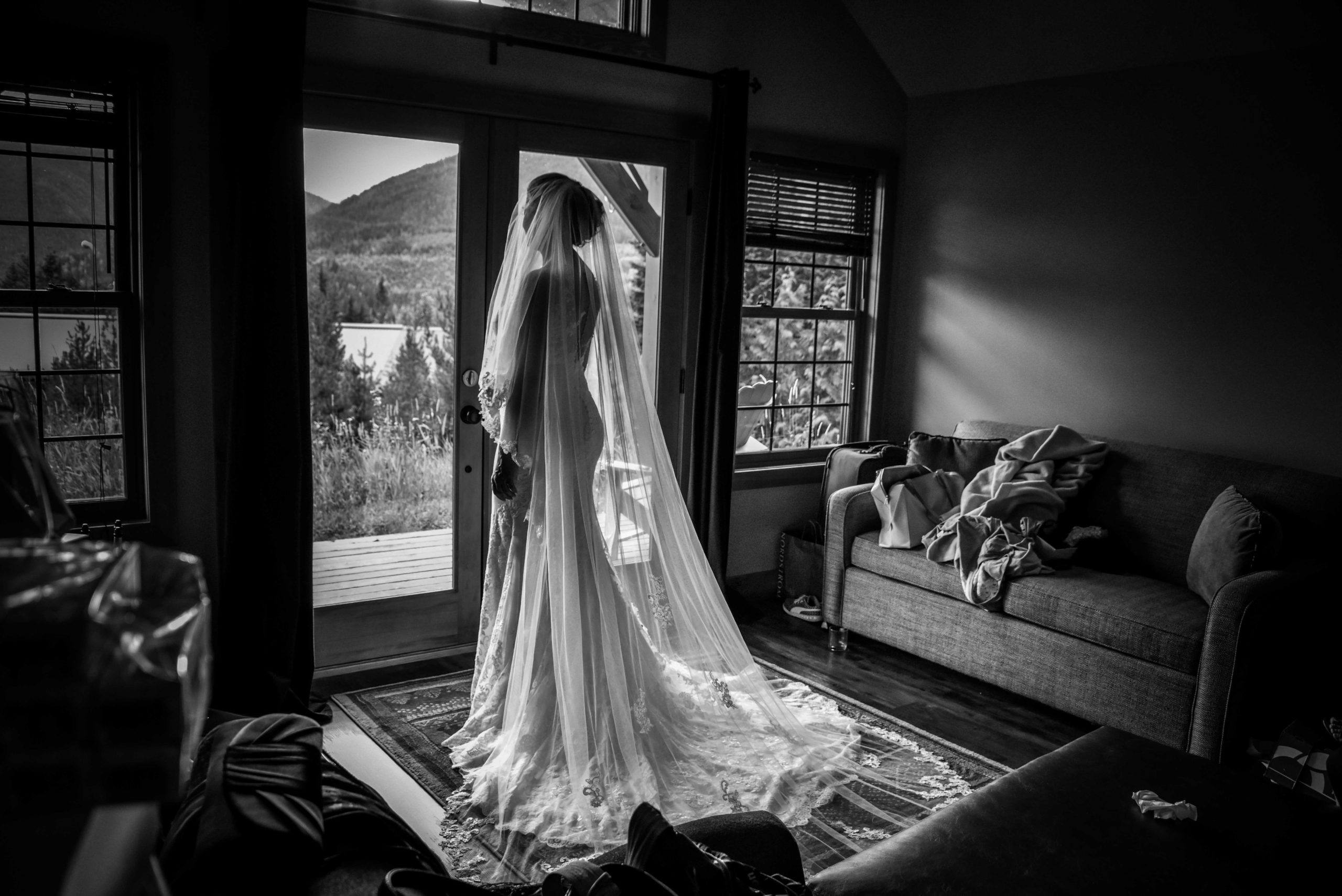 Bride standing in side a cabin looking outside in her dress