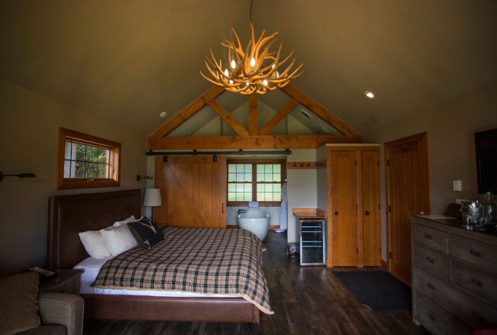Interior of cabin with a large bed, barn door to bath and hardwood floors