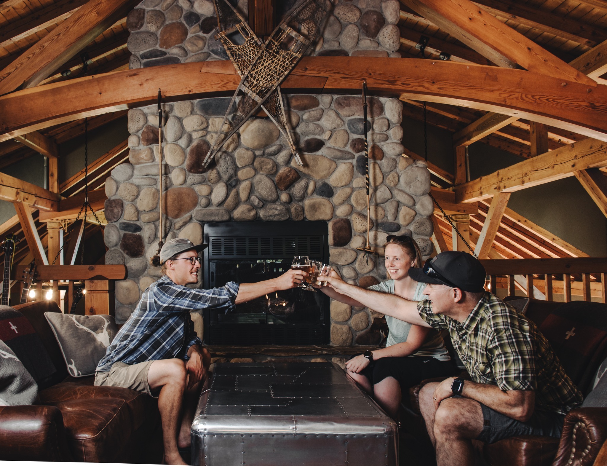 group cheersing their beers in a lodge by a stone fireplace