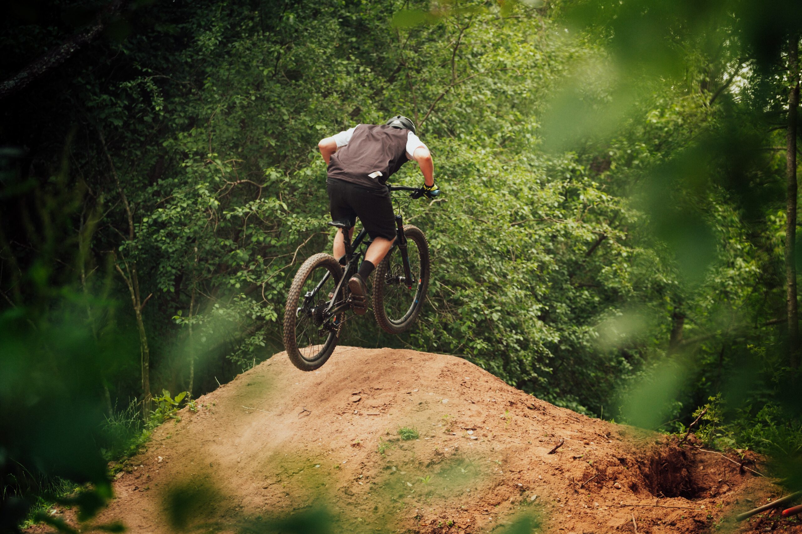 mountain biker hitting the roller in the forest on a trail